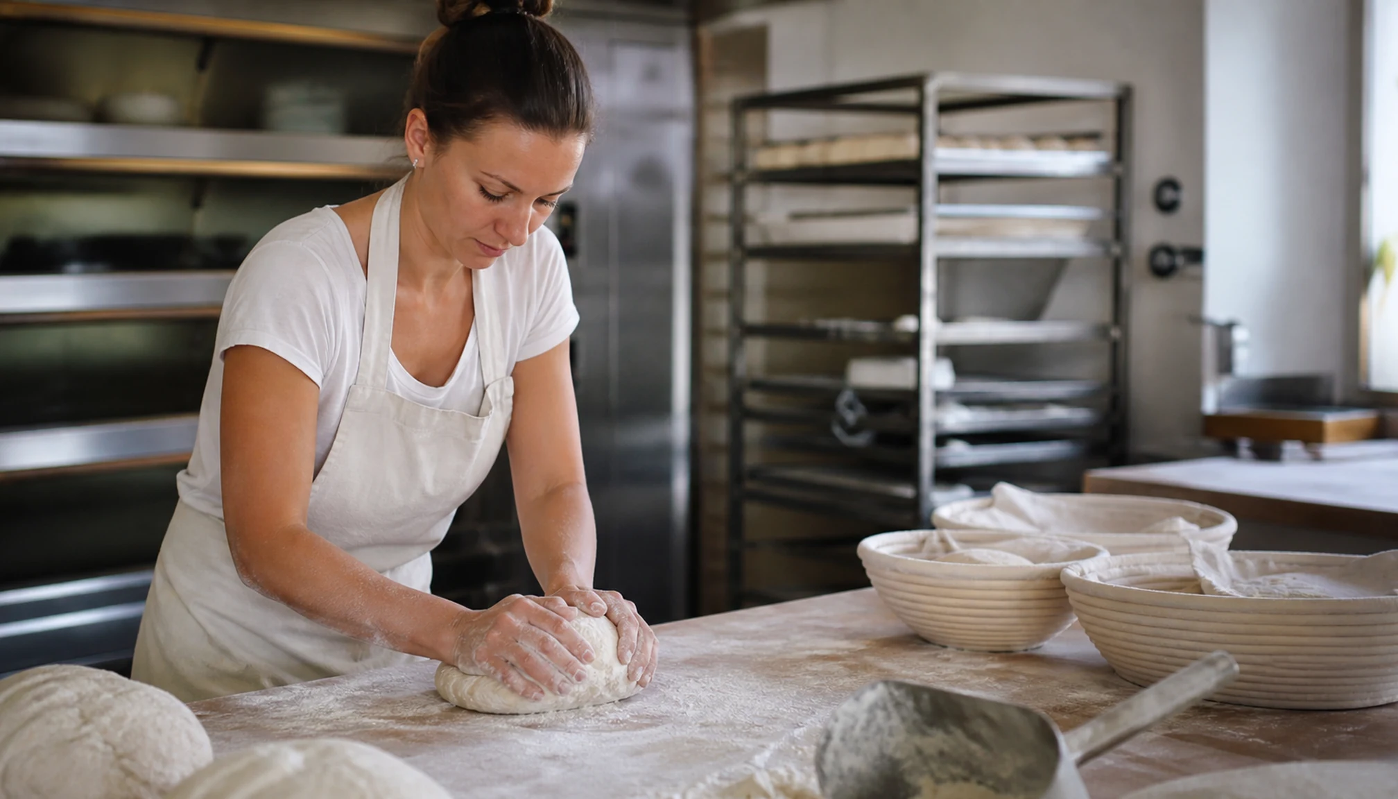 Une boulangère pétrit une pâte dans un fournil artisanal